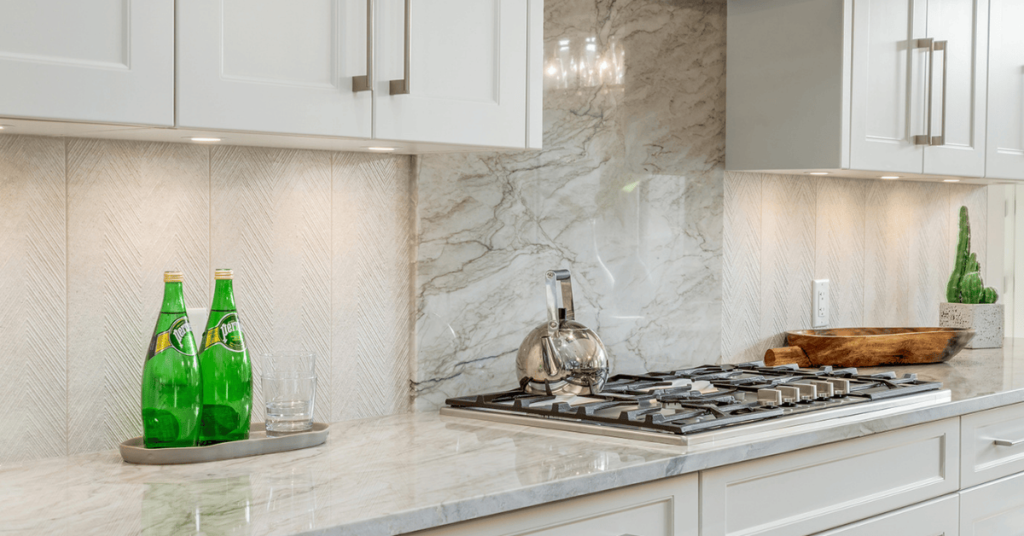 Kitchen with white marbled vertical applied quartz backsplash behind the range by Superior Cabinets, expected to be on trend in 2022.